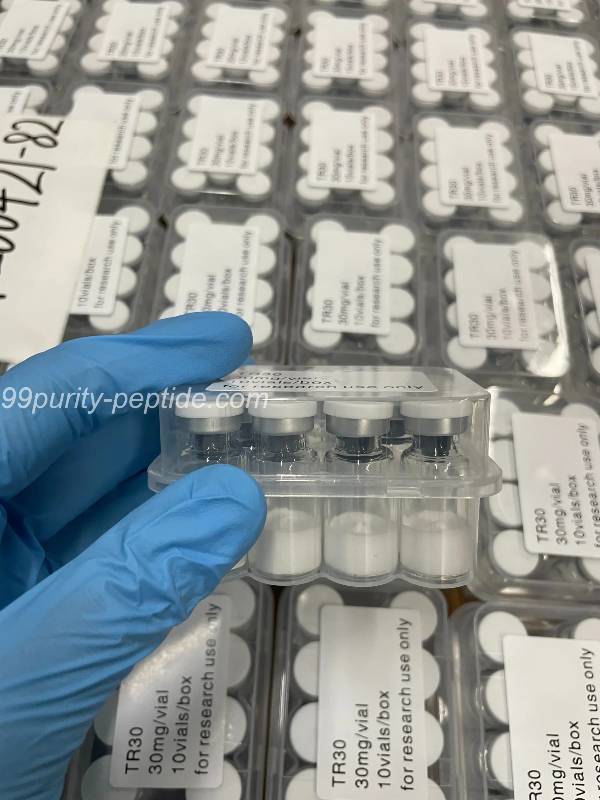Specialist holding a HGH vial in the 99Purity-Peptide warehouse for physique research.